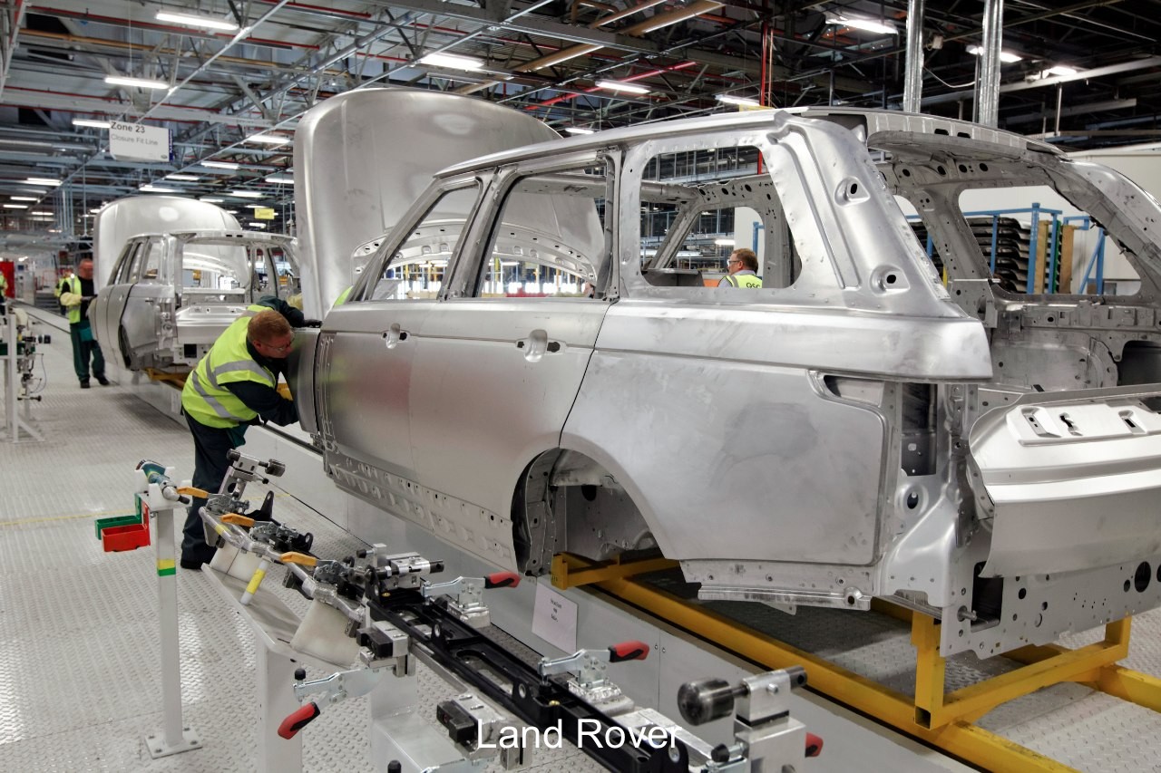 Modern factory, brightly lit. More robots than humans. 