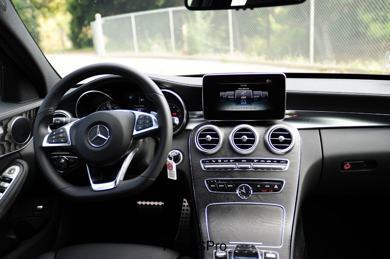 The center console is entirely covered in wood and it appears to be a waterfall of black oil. Notice the flat steering wheel.